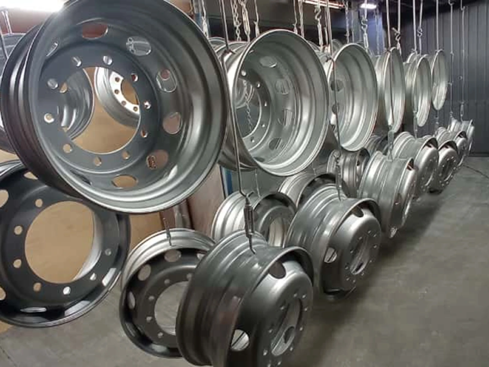 Zawieszone felgi stalowe w trakcie lakierowania proszkowego na linii produkcyjnej