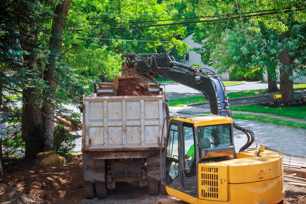 Usługi koparką: załadunek ziemi do wywrotki na terenie budowy