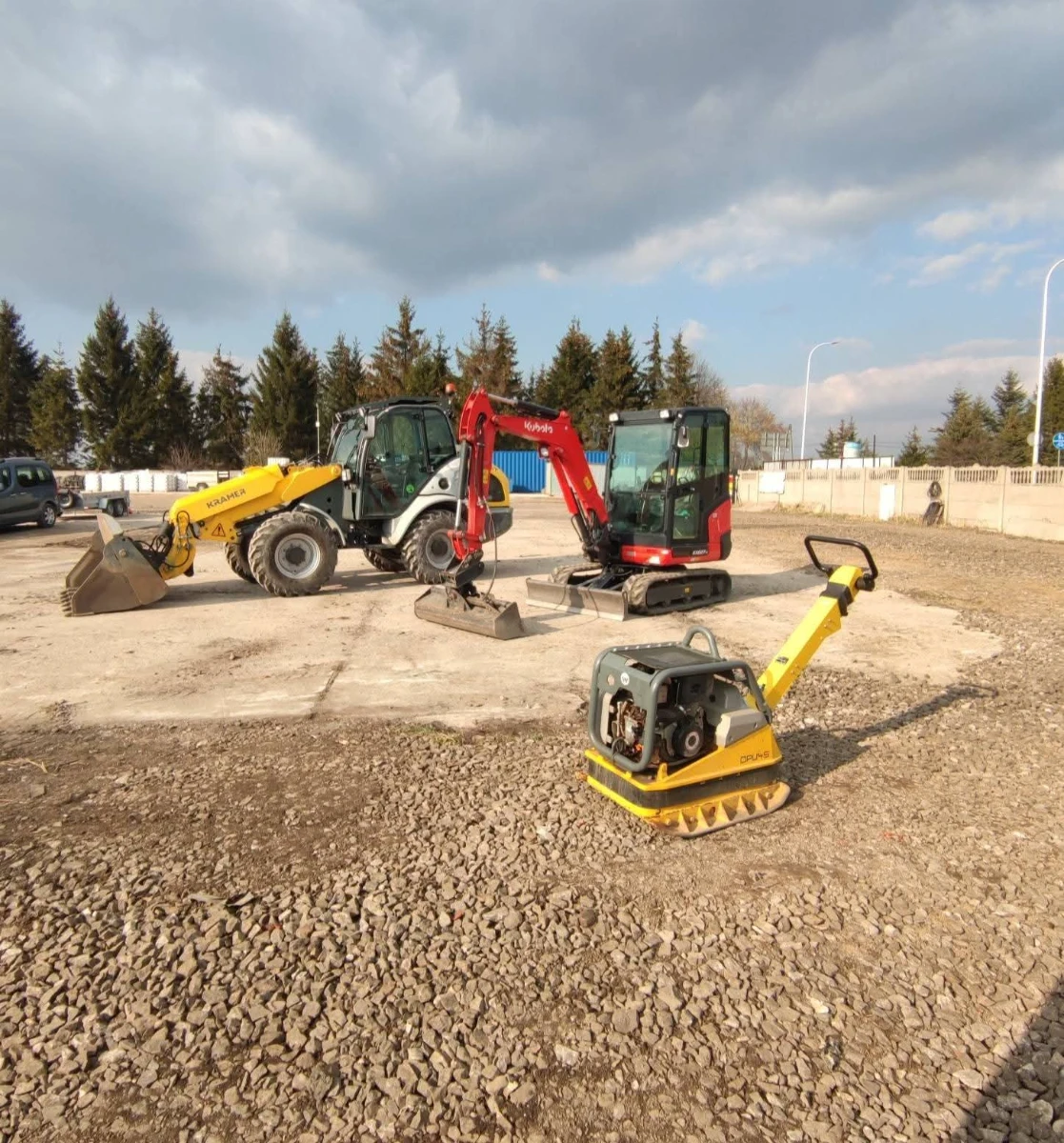 Telehandler, mini-koparka oraz zagęszczarka płytowa stojące na przygotowanym podłożu z kruszywa